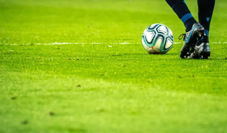 A football resting on the grass beside the pitch