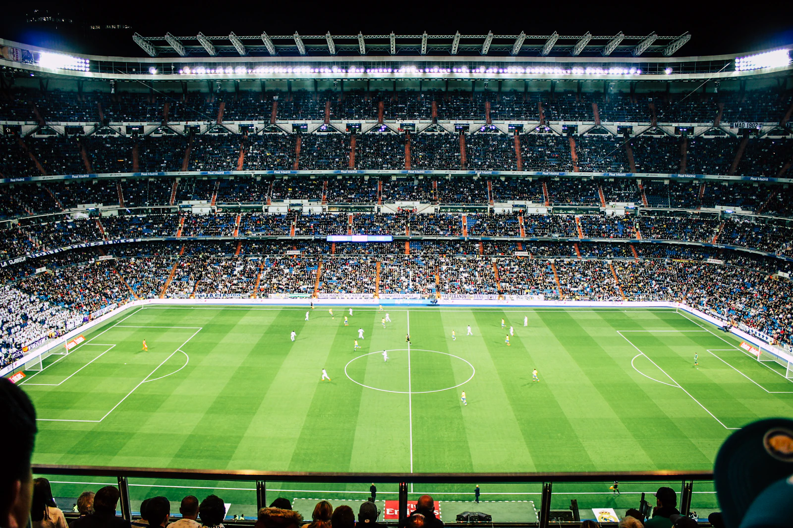 A packed football stadium illuminated for an evening match