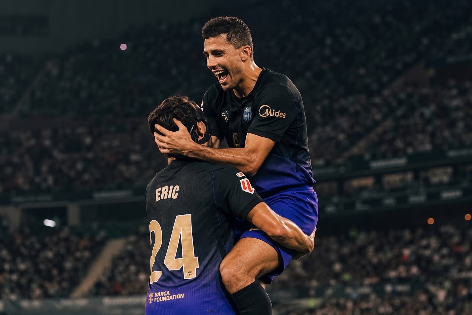 Two Barcelona players embracing in celebration on the pitch.