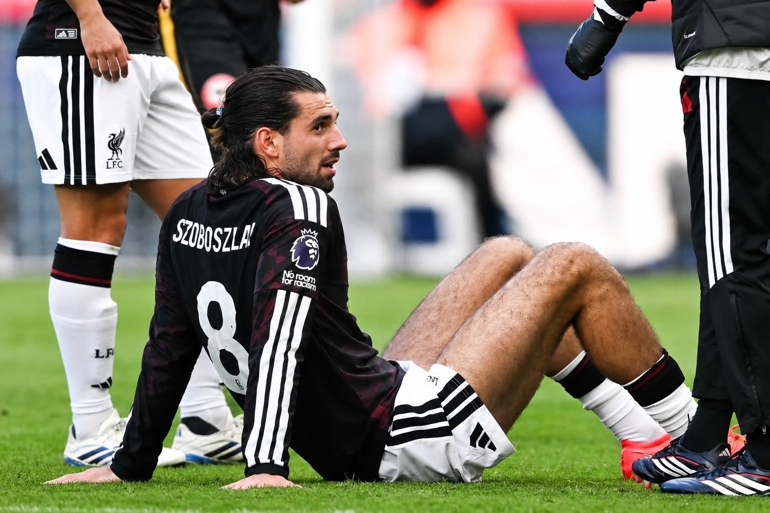 Liverpool number 8 Szoboszlai seated on the pitch during a stoppage.